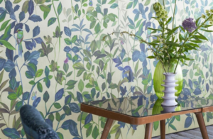 salon con silla y mesa de cristal en la pared un mural con hojas en verde y azul