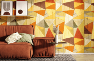 salon con sofá mesilla y cuadro y papel pintado con figuras geometricas en tonos calidos